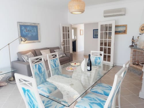Moderno apartamento de praia no Algarve com mesa de jantar em mármore, cadeiras estofadas em azul, sofá cinzento e sala aberta