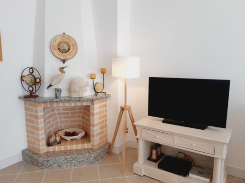 Sala de estar aconchegante de apartamento na Praia do Algarve com lareira, TV, luminária e objetos de decoração