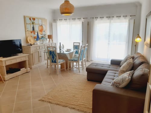 Sala de estar moderna do apartamento na Praia do Algarve com sofá de couro marrom, zona de refeições e vista para o oceano em Villalusa, Portugal