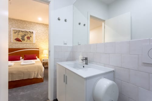 Lisbon Poets Inn Suite Casal bathroom with sink and toilet adjoining bedroom with red accents