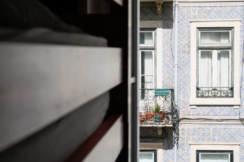Lisbon hostel balcony view with historic blue-tiled facade and wrought iron railings