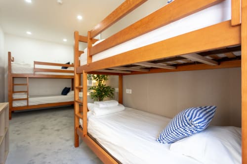 Wooden bunk beds in a bright hostel dorm room at Lisbon Poets Inn with white bedding and blue pillow