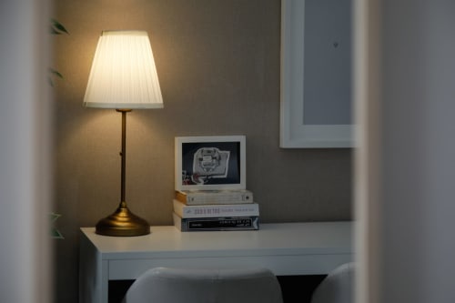 Desk with brass lamp, vintage computer and stacked books in Lisbon Poets Inn hostel room