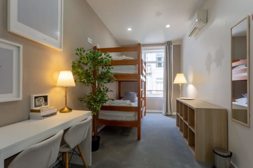 Quad room at Lisbon Poets Inn hostel with bunk beds, desk, and city views from windows