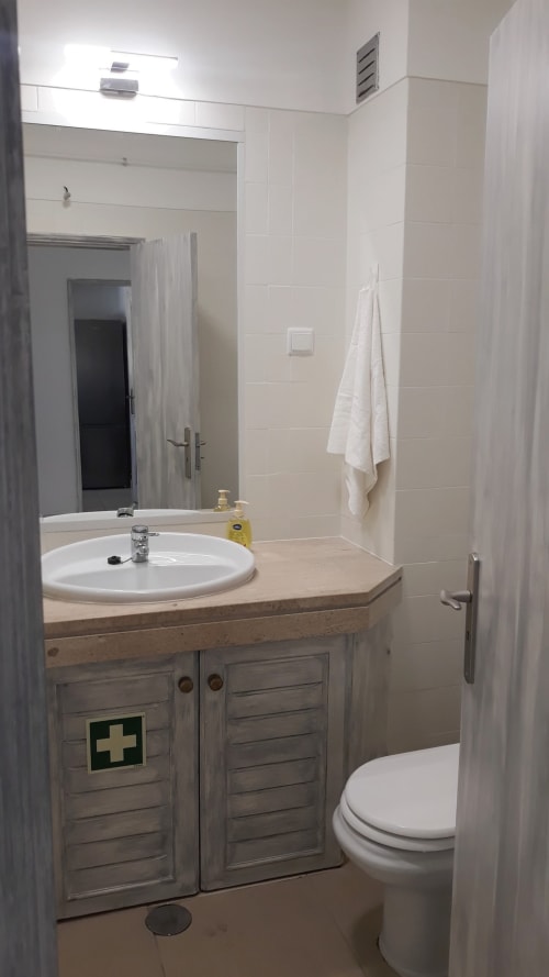 Banheiro moderno do apartamento MARESIA na Algarve Beach Holidays com azulejos brancos, móvel de madeira e pia redonda