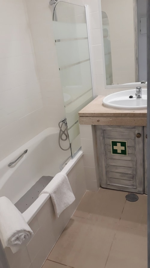 Banheiro moderno no apartamento de praia em Maresia, Algarve Beach Holidays, com azulejos brancos, box de vidro e gabinete em madeira