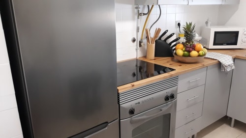 Cozinha moderna do apartamento de praia MARESIA, Algarve, com eletrodomésticos em aço inox e bancadas de madeira