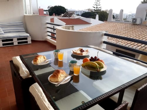 Pequeno-almoço no terraço do apartamento Maresia em Algarve com pastéis, sumo e frutas frescas com vista sobre a cidade