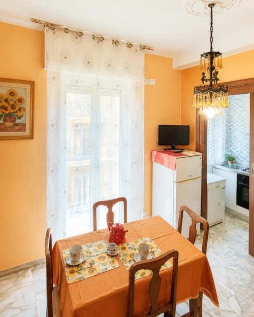 Area living dell'Appartamento La Fenice con pareti arancioni, tavolo in legno e vista sulla cucina a Varigotti, Italia