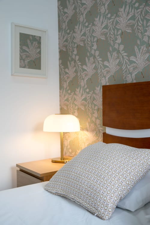Modern hostel bedroom at Lisbon Poets Inn with king bed, patterned wallpaper, bedside lamp, and wooden headboard