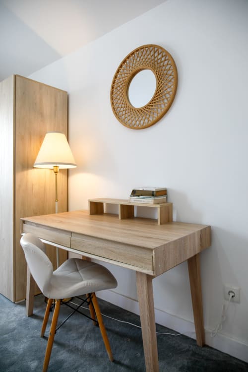 Modern workspace with wooden desk, white chair, lamp, and woven mirror at Lisbon Poets Inn hostel