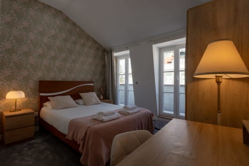 Spacious king bedroom at Lisbon Poets Inn with city views, wooden bed, desk, warm lighting, and balcony access in Lisboa