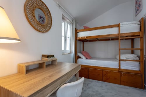 Bright hostel bedroom at Lisbon Poets Inn with wooden bunk bed, desk, window, and warm lighting
