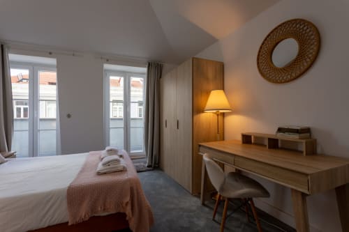 Lisbon Poets Inn hostel king room with city view balcony, wooden desk, lamp, and woven mirror decor