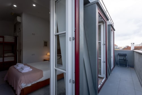 King size bedroom with city views and shared terrace at Lisbon Poets Inn hostel, featuring white towels on bed and access to