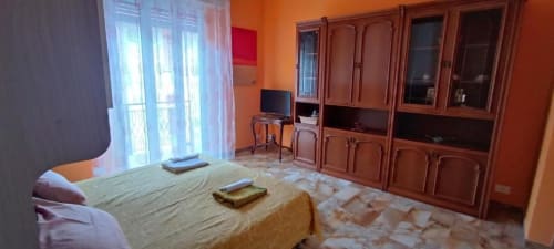 Camera da letto La Fenice di Welcome Holiday a Varigotti con armadio in legno, TV, pareti arancioni e vista sulla città