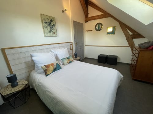 Bright cottage bedroom at Les Prairies du Val d'Amboise with white bed, exposed beams, wooden headboard, and rustic décor in