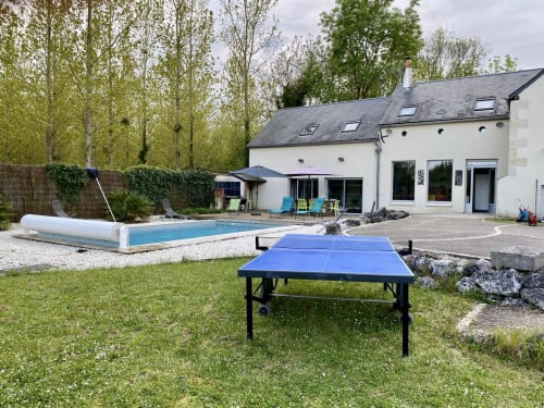 Cottage garden with blue ping pong table, heated swimming pool, and lounging umbrellas at Les Prairies du Val d'Amboise,