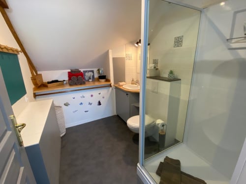Modern bathroom in Les Prairies cottage with white vanity, toilet, and large walk-in shower with glass enclosure