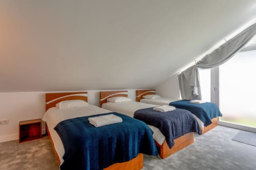 Spacious king-size bedroom at Lisbon Poets Inn with three single beds, blue bedding, wooden headboards, and skylight access