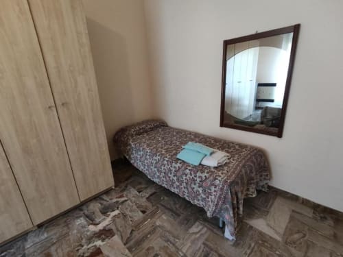 Piccola camera con letto singolo, armadio in legno e specchio presso la Residenza Adalgisa a Finale Ligure