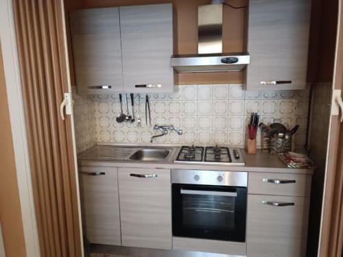 Cucina compatta con piano cottura a gas, forno, lavello e mobili color beige in Residenza Adalgisa, Finale Ligure