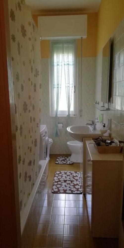 Bagno luminoso con pareti gialle, lavandino, water e finestra con persiane a Welcome Holiday Varigotti
