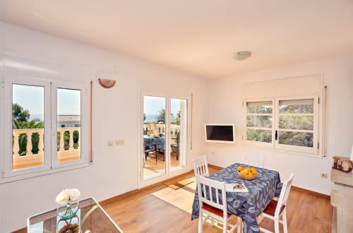 Comedor luminoso con suelos de madera, vistas al mar a través de puertas francesas y terraza amueblada en Experiencias Encant, Calafat.