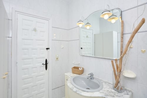Baño moderno en Experiencias Encant B&B en Calafat con azulejos blancos, lavabo de mármol, espejo y lámparas colgantes