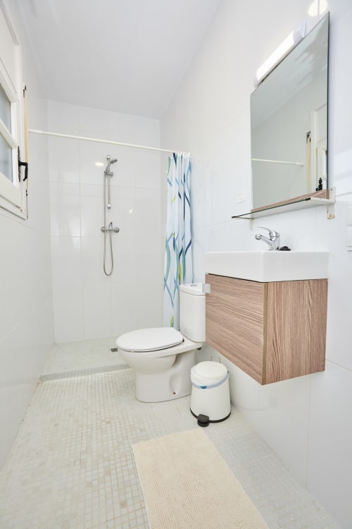 Baño moderno en Experiencias Encant BnB en Calafat con azulejos blancos, mueble de madera y ducha de efecto lluvia