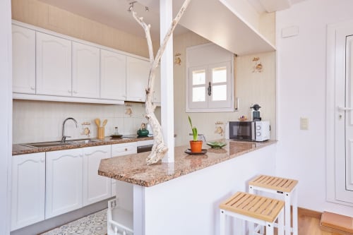 Cocina moderna con muebles blancos y encimera de granito en Experiencias Encant B&B en Calafat, España