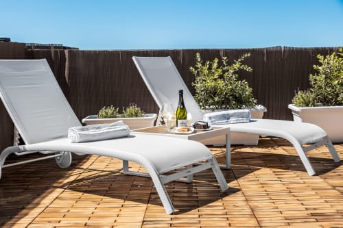 Terrazza sul tetto Bluemoon Sardegna con lettini bianchi, bottiglia di vino e piante a Cagliari