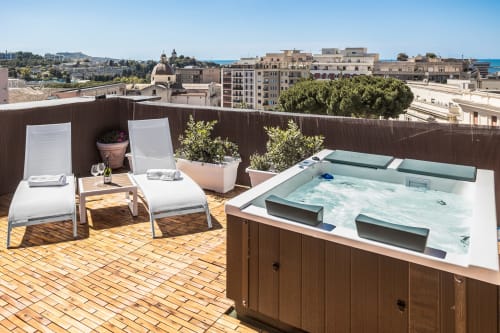 Terrazza sul tetto Bluemoon Sardegna a Cagliari con vasca idromassaggio, lettini e vista sulla città