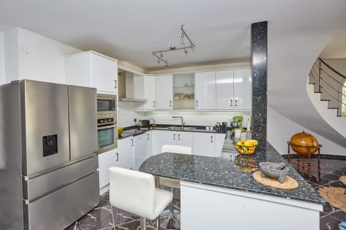 Cocina moderna en Experiencias Encant B&B en Calafat con armarios blancos, encimeras de granito oscuro y electrodomésticos de acero inoxidable