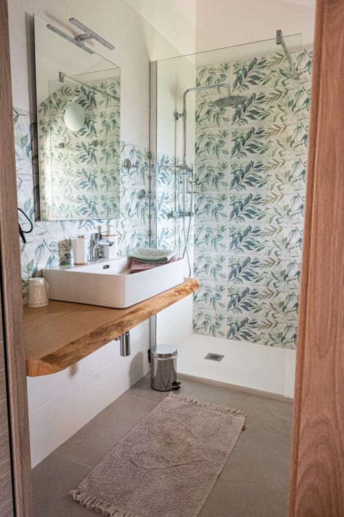Bagno moderno con piastrelle a motivi botanici, lavandino bianco, mobile in legno e doccia in vetro presso AgriBio Villa