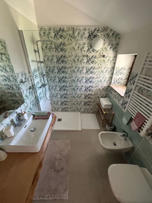 Bagno della camera Anemone presso AgriBio Villa Ribes con carta da parati botanica, lavabo, bidet e doccia ad Altamura