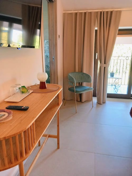 Camera moderna di AgriBio Villa Ribes con scrivania in legno, sedia turchese e balcone con vista sul giardino di Altamura