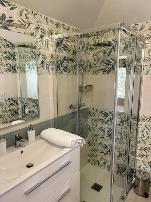 Bagno moderno con carta da parati botanica, lavabo bianco e doccia in vetro presso AgriBio Villa Ribes ad Altamura