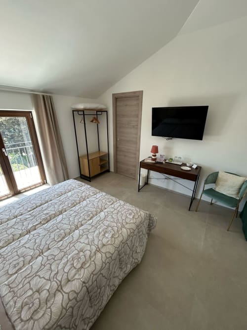 Camera moderna di AgriBio Villa Ribes con vista giardino, letto, TV, scrivania e accesso al balcone ad Altamura