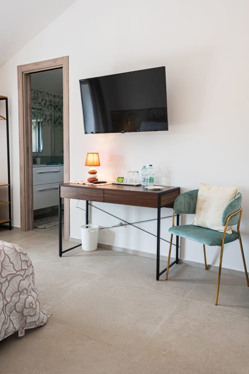 Camera moderna presso AgriBio Villa Ribes ad Altamura con scrivania, TV, poltrona verde e accesso al bagno