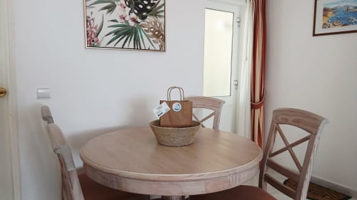 Sala de jantar do apartamento Sweet Home Oasis com mesa redonda de madeira, cadeiras e decoração costeira em Portimão