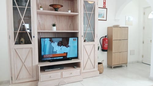 Sala de estar moderna com painel de TV em madeira clara, televisão de tela plana, armários com portas de vidro e prateleiras embutidas
