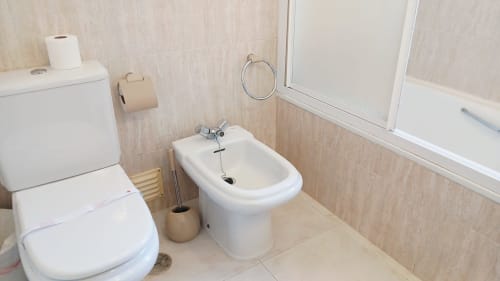 Banheiro moderno com vaso sanitário, bidê, box de duche e azulejos bege no apartamento Sweet Home Oasis Parque em Portimão