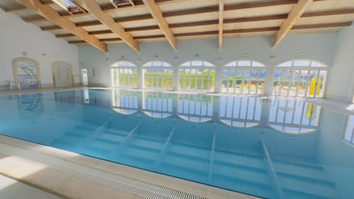 Espaçosa piscina interior do Sweet Home Oasis Parque em Portimão com vigas de madeira e grandes janelas