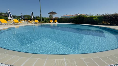 Piscina compartilhada cristalina do Sweet Home Oasis Parque em Portimão com espreguiçadeiras e guarda-sóis amarelos
