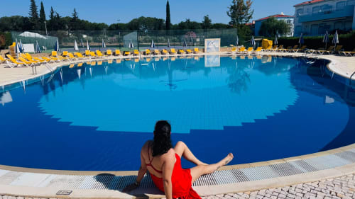 Mulher de vestido vermelho à beira da piscina com águas cristalinas do Sweet Home Oasis Parque em Portimão, Portugal