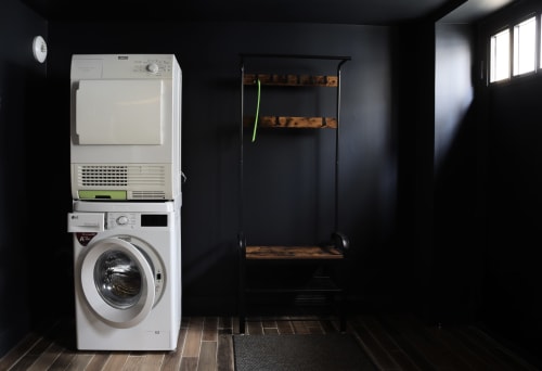 Laundry room with stacked white LG washer-dryer and wooden shelving rack in La Maison d'Augustin loft, Mont-de-Marsan