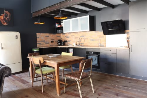 Modern kitchen and dining area in La Maison d'Augustin loft in Mont-de-Marsan with wooden table, black cabinetry, and brick
