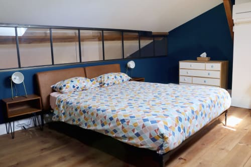 Bright loft bedroom at La Maison d'Augustin with blue walls, patterned bedding, wooden furniture, and skylights in