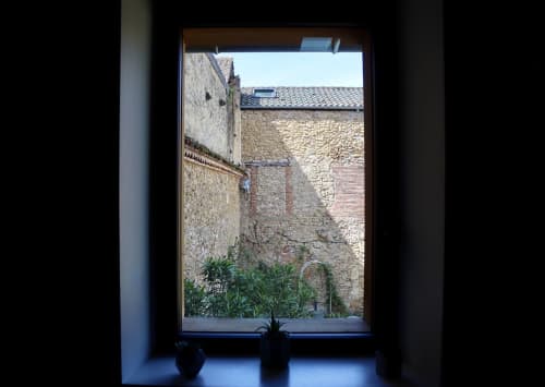 Window view from La Maison d'Augustin cottage showing stone courtyard walls and potted plants in Mont-de-Marsan